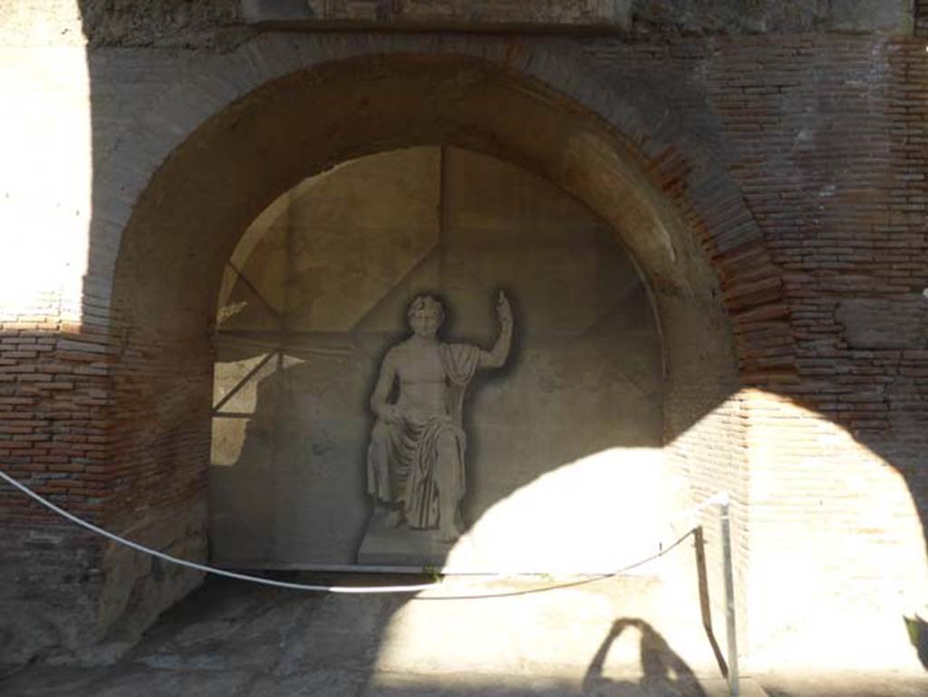 Herculaneum, September 2015. Looking north towards the arch leading to the east portico of the Augusteum, also known as the Basilica.
The imitation seated figure is Augustus, shown as Jove on his throne MANN 6040.