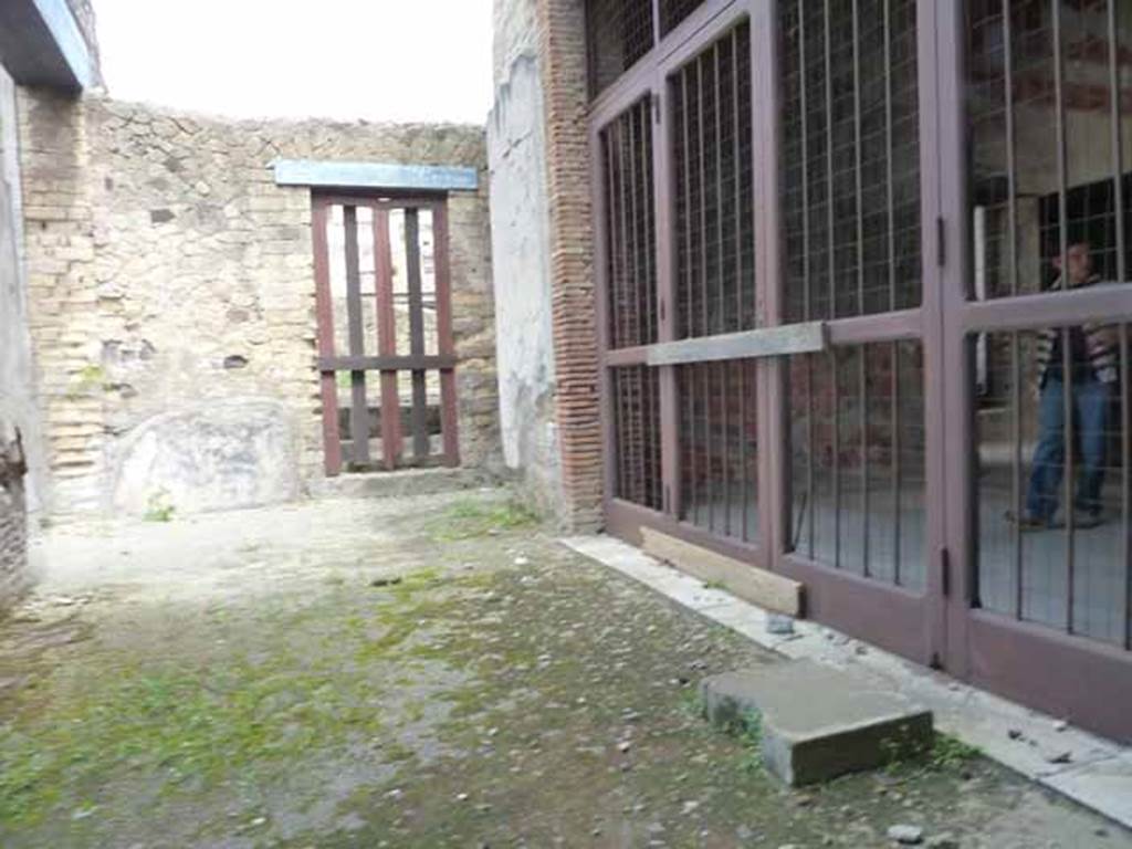 III.11 Herculaneum. May 2010. 
Looking from doorway in north wall of room 8, north across the east portico, towards a doorway in III.8. 
The doorway on the right is from the tablinum, room 9.
