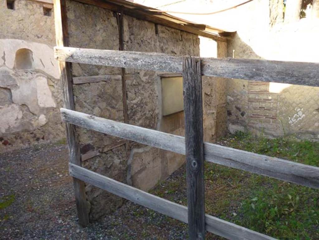 IV.15/16, Herculaneum, October 2012. Looking north-west towards room 6, used by the customers (behind the wooden fence).  On the left is the west wall of room 7. Photo courtesy of Michael Binns.
