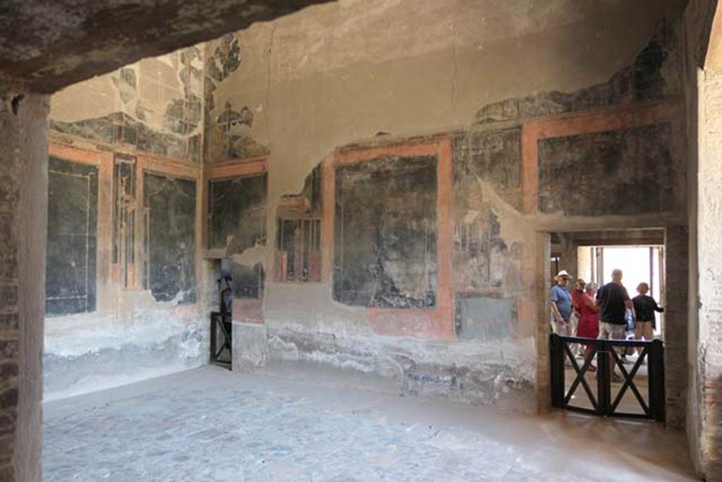 IV.21, Herculaneum, June 2017. Looking towards east wall of triclinium 5, with doorway to atrium, on right.
On the socle (plinth/dado, zoccolo) of the east wall at the south end, to the left of the doorway to the atrium, is a blue painted panel.
On this panel, is a painting similar to the other blue panel paintings of masks, but very badly faded, and left in situ.
Photo courtesy of Michael Binns.

