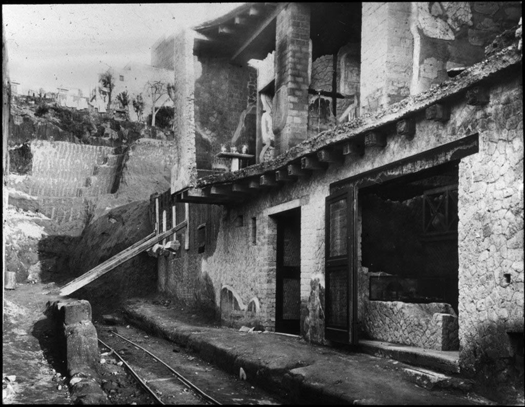 Cardo IV Superiore, Herculaneum. Looking north along Cardo IV Superiore towards Insula V., during excavations.1935.
Photo by Fratelli Alinari (I.D.E.A.). Alinari No 43312.
V.6 the doorway to the wine/food shop is on the right.
V.7, the doorway to Casa di Nettuno e Anfitrite or House of Neptune and Amphitrite, is in the centre.
V.8, is the area still being excavated beneath props holding wall up, on left.
Used with the permission of the Institute of Archaeology, University of Oxford. File name instarchbx116im012 Resource ID 42241.
See photo on University of Oxford HEIR database
