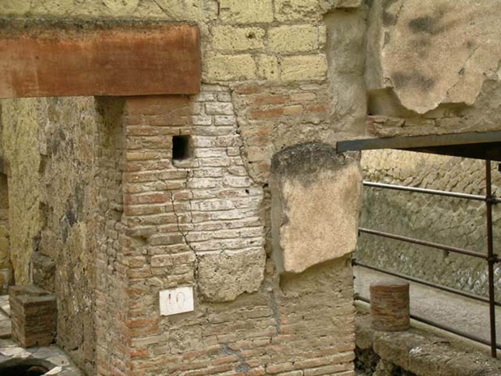 V.10, Herculaneum. May 2005. Front north facade on west side of shop doorway, on corner of Decumanus Maximus and Cardo IV. 
Photo courtesy of Nicolas Monteix.
