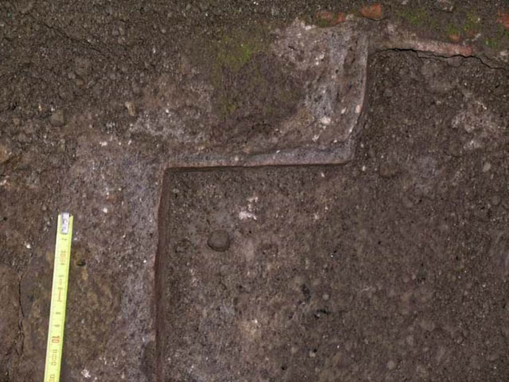 V.10, Herculaneum. December 2004. Detail of drain, or pit, on north side of counter in shop-room. Photo courtesy of Nicolas Monteix.

