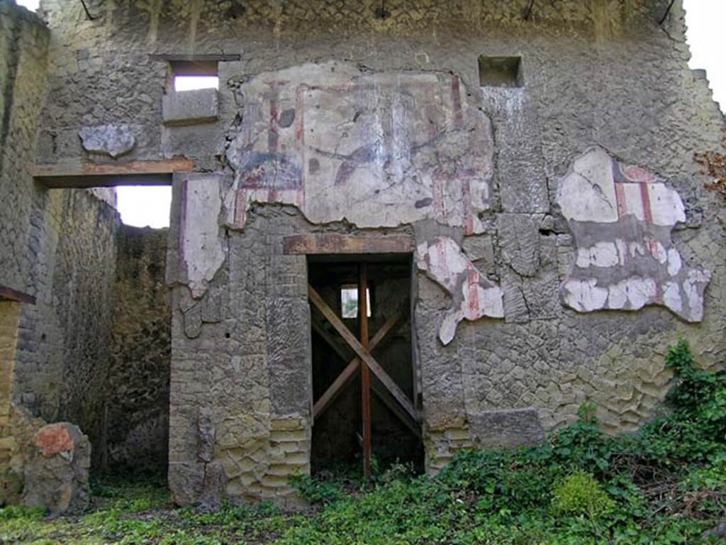 V.11 Herculaneum. May 2004. Looking towards west wall of atrium, with details of square holes for heavy support beams of the roof and compluvium. 
The west wall clearly showed the decorative composition, one can still clearly see a peacock sitting on the large garland, on the panel painted with a white background.  
Photo courtesy of Nicolas Monteix.

