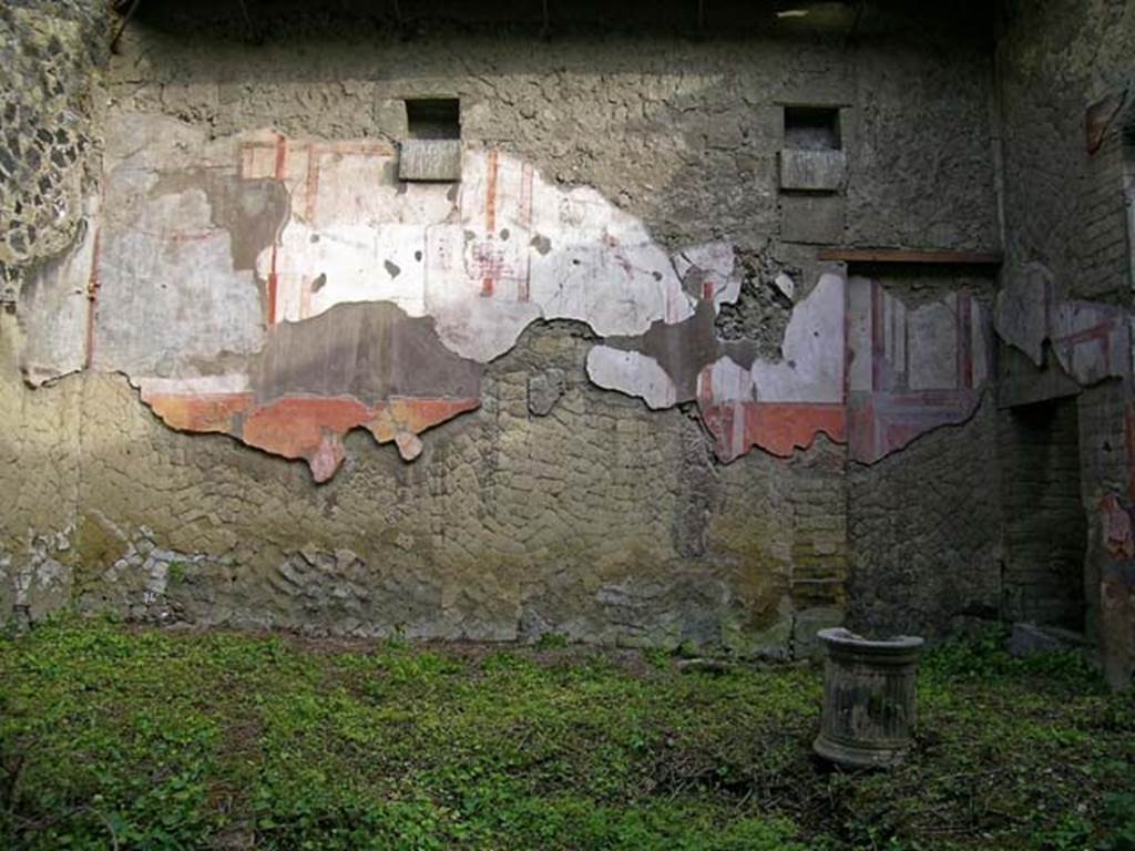 V.11, Herculaneum. May 2004. Looking towards east wall of atrium. Photo courtesy of Nicolas Monteix.
According to Maiuri, this atrium showed the rare detail of the proof of the height of the compluvium.
Still preserved simmetrically on both the east and west walls, were the large square holes for the heavy support beams of the roof. 
Below these holes protrude square blocks of tufa forming a small shelf for each hole, to better support the weight of the two heavy beams, they almost formed a cubic capital by crowning the four pillars clamped in the wall to strengthen the weight of the compluvium. 
