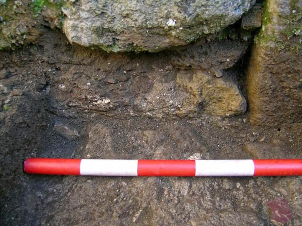 VI.25, Herculaneum. May 2004. Detail of an investigation beneath the floor of the shop-room. 
Detail, looking west on the west side below the north end of the threshold.  Photo courtesy of Nicolas Monteix.
