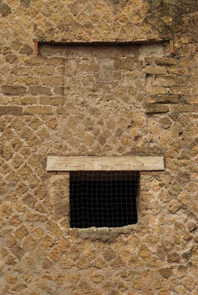 A large brown brick building next to a stone wall

Description generated with high confidence