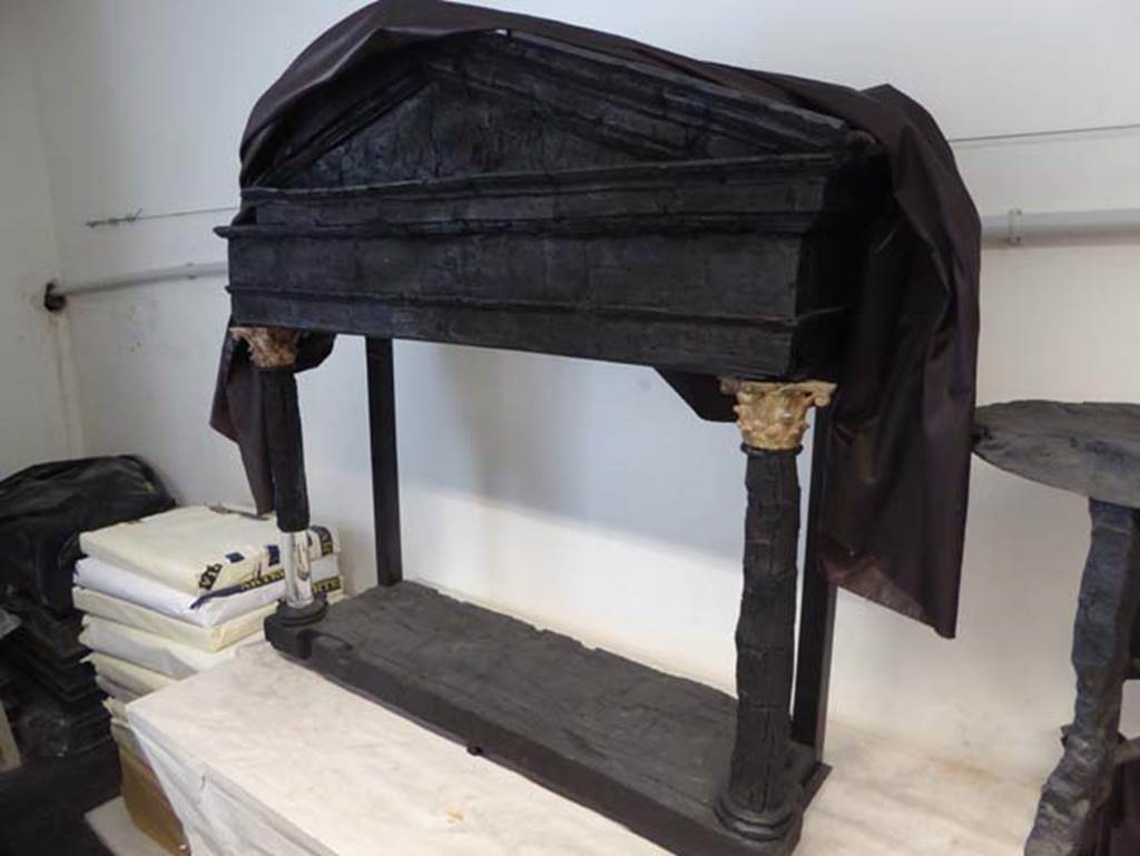 VI.13, Herculaneum, September 2016. Wooden shrine, found placed against a wall in the “Salone nero”.
Photo courtesy of Michael Binns.
Guidobaldi wrote that found in this room was a wooden lararium with capitals of painted marble and red lead, and a small marble table with the head of a satyr on the foot.
See Guidobaldi, M.P, 2009: Ercolano, guida agli scavi. Naples, Electa Napoli, (p.106).
According to Deiss, found in the black saloon – “was another miraculous wooden survival: a shrine in the form of a miniature temple.
The fluted columns were of wood, the capitals of marble.
Preserved within are the statuettes typical of a lararium maintained by people who remained devout in the old Roman faith”.
See Deiss, J.J. (1968). Herculaneum: a city returns to the sun. U.K, London, The History Book Club, (p.64).