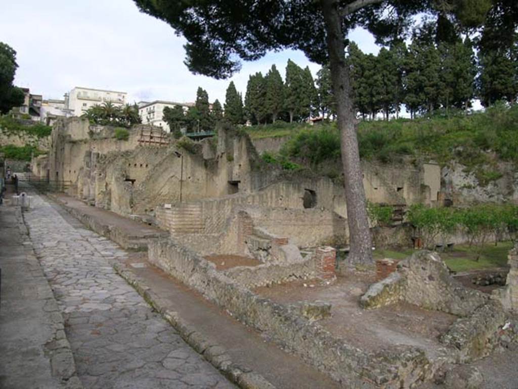 Ins. Orientalis I.3, Herculaneum, May 2004.
Looking towards area of house and garden of Telephus Relief on its north-western side, lower centre right.
The aedicula lararium can be seen against the north wall of the garden area.
This rustic area occupied all the area on the north side of the house.
In the centre of the photo, would be the area of room C, on its south side would be room A, with a doorway into room B on its south side.
Room D with the three stoves, is on the extreme right, behind room B. On the left is Cardo V, looking north.
Photo courtesy of Nicolas Monteix.
The rustic area was composed of a stable with ramp, and a garden, with some rooms on the south and west sides.
These rooms may have been turned into a commercial use, during their last days.
In one of the rooms, (room B), the floor was completely covered with tiles, as often seen in a workshop of a laundry.
In another, (room D), a set-up of three stoves would probably have been used for the industry carried out in workshop B.