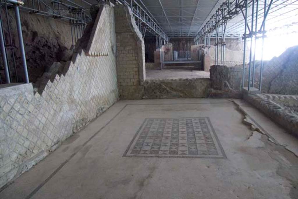 Villa dei Papiri, Herculaneum. July 2010.
Looking east across room (r), at the rear of room (s), on right. Photo courtesy of Michael Binns.
According to Guidobaldi and Esposito, a limited excavation survey was carried out in room (s) to verify the presence of the pavement.
The survey, carried out along the east wall, confirmed that the pavement of the room, in opus tessellatum, must have rested upon a flat floor supported by wooden beams, which collapsed at the time of the 79 C.E. eruption.
It is probable, therefore, that the floor is still in situ, but subsided under several dozens of centimetres of collapsed material.
See Esposito D. and Guidobaldi M., 2010. New Archaeological Research at the Villa of the Papyri, in the Villa of the Papyri at Herculaneum. Berlin: De Gruyter, p. 28, notes 14 and 15.