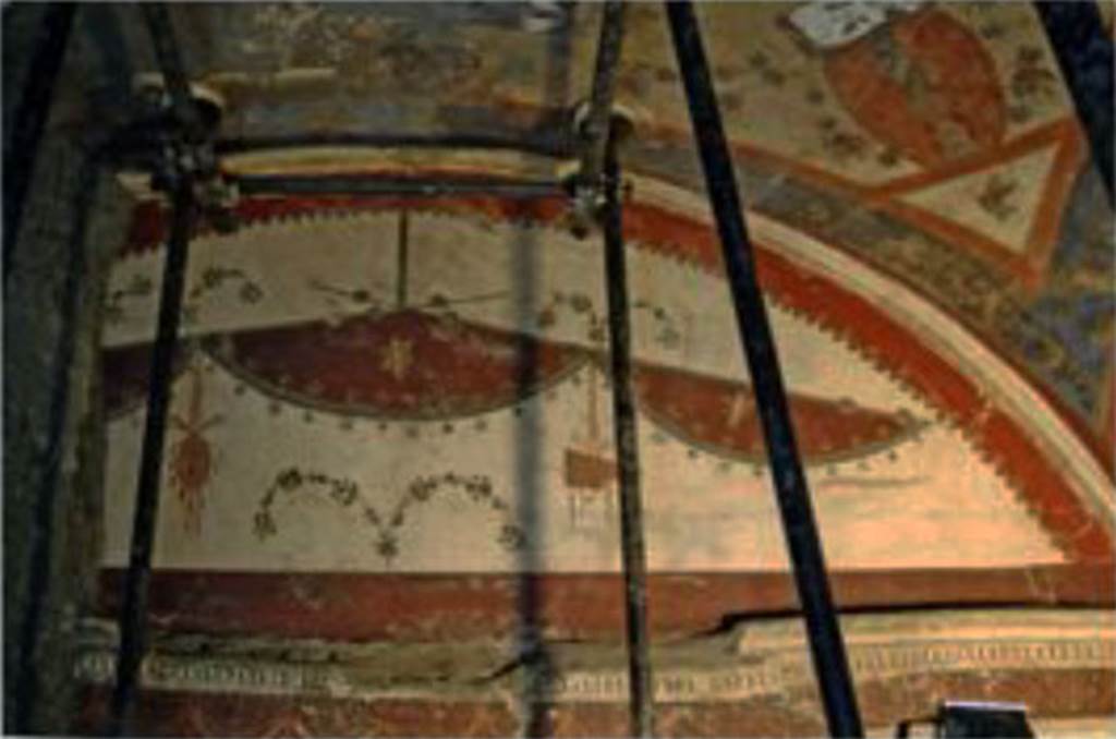 Villa dei Papiri, Herculaneum. July 2010. Room (I) on lower terrace, antechamber east wall. Lunette decoration in fourth style. A tambourine and pan pipes hang from crossed vegetal thyrsi. A violet cloth hangs on the thyrsi forming oval areas with flying cupids depicted in the centre of each.
See Esposito D. and Guidobaldi M., 2010. New Archaeological Research at the Villa of the Papyri, in the Villa of the Papyri at Herculaneum. Berlin: De Gruyter, p. 37. 
