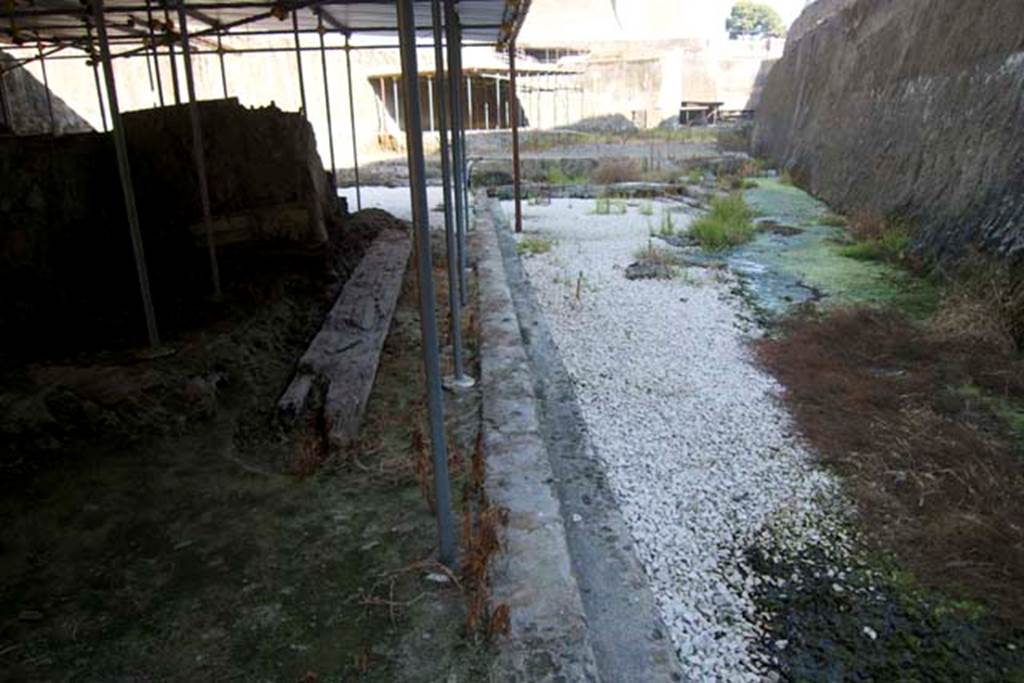 Villa dei Papiri, Herculaneum. July 2010. 
Looking east along part of the monumental structure/hall, on left, with area of pool, on right. Photo courtesy of Michael Binns.

