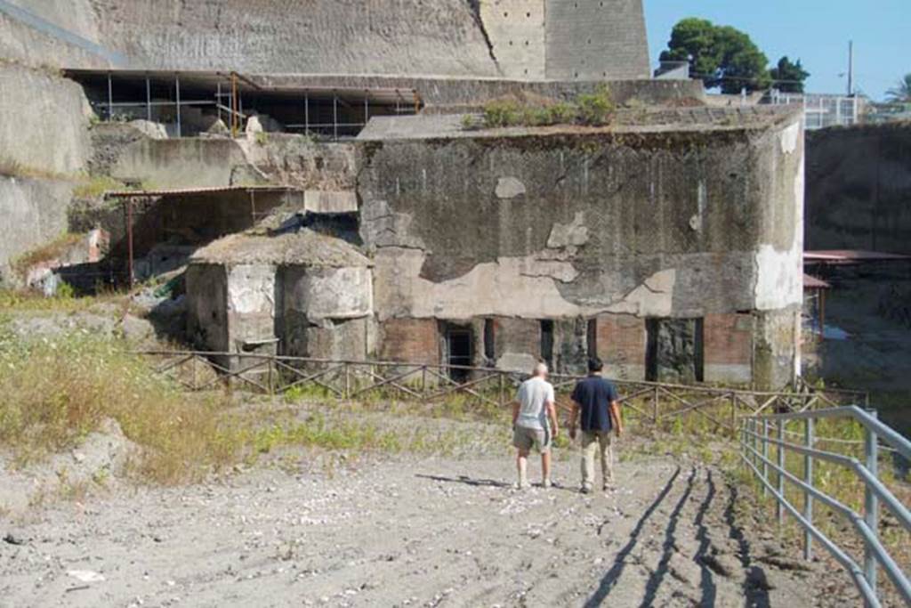 South-western baths, Herculaneum. July 2010. Looking north-east. 
The pool building 1 is to the right and rooms 3 and 4 are to the left of it.
In the upper left corner can be seen the excavation of the upper floor of the House of the Dionysiac Reliefs, not yet fully excavated.
Photo courtesy of Michael Binns.
Guidobaldi wrote, “On the upper terrace (best seen as one exits the site), 9 rooms have been excavated belonging to one or more dwellings and partly damaged by the passages of the tunnels.” 
See Guidobaldi, M.P, 2009: Ercolano, guida agli scavi. Naples, Electa Napoli, (p.132-3).
